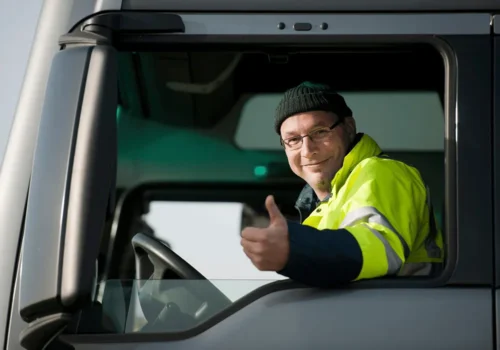 تصویر مربوط به یک آقای راننده ماشین سنگین است که پشت فرمون نشسته و با دستش علامت لایک داده با لبخند